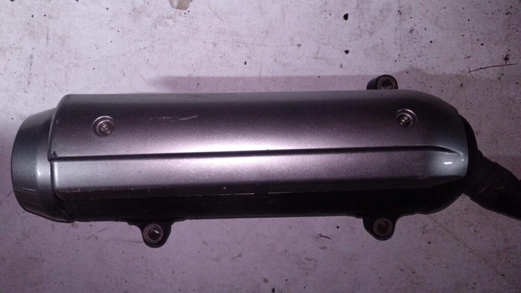 Vista lateral de silenciador plateado para scooter Yamaha XMAX 125, años 2016-2017, sobre superficie texturizada.