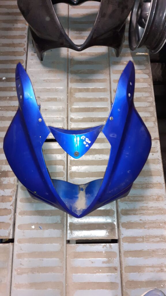 Vista exterior del carenado frontal azul monobloque para Suzuki GS 500 F. Se detallan los orificios de fijación para los retrovisores y la cúpula, así como el puente de unión inferior que rodea la óptica.