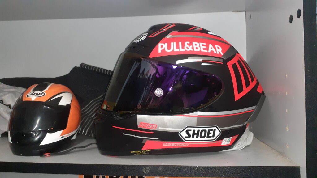 Primer plano de un casco Shoei X-Spirit III réplica de Marc Márquez 93, en color negro mate con detalles rojo fluorescente y patrocinador Pull&Bear. Se aprecian los logotipos de Dave Designs, Shoe, y el número 93 en el lateral.