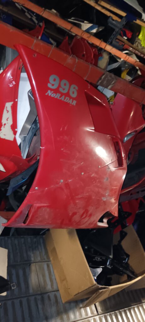 Detalle de remaches en el carenado lateral izquierdo de Ducati 996 rojo reparado.