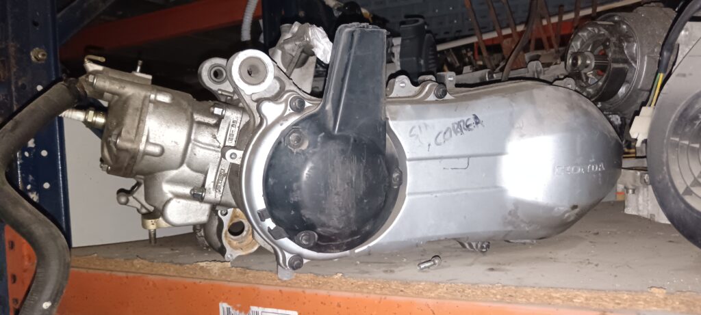 Motor completo Honda Pantheon 150 2T con tapa de variador original Honda. Vista lateral del bloque motor de dos tiempos refrigerado por agua. Recambio verificado por profesionales con 20 años de experiencia.