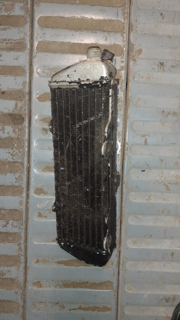 Vista frontal de radiador izquierdo para Beta RR 50 Racing y Factory. Panal de aberturas de refrigeración en aluminio negro. Repuesto original usado para moto de enduro disponible en Vayafaba por 100 €.