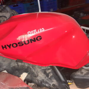 Depósito de combustible Hyosung GTR 125 rojo de segunda mano, recambio original recuperado con referencia manuscrita en el lateral, ubicado en estantería de taller.