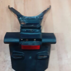 Vista frontal del portamatrículas original para Yamaha Fazer 600 (2007). Incluye el catadióptrico rojo y los huecos para intermitentes, en buen estado de conservación.