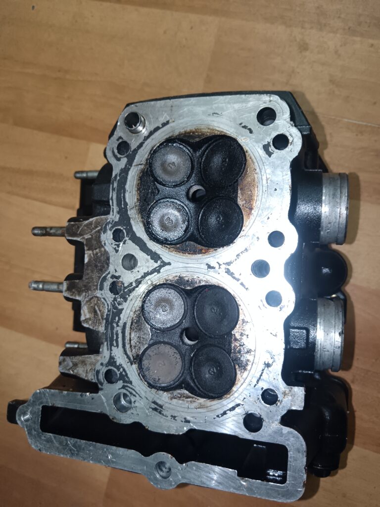 Plano inferior de culata Kawasaki ZZR 250 mostrando las cámaras de combustión y el estado de las ocho válvulas.