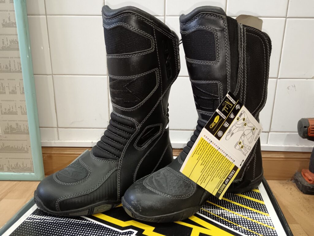 Par de botas de moto negras impermeables AXO TRACE WP talla 41, con etiqueta colgante en la bota derecha.