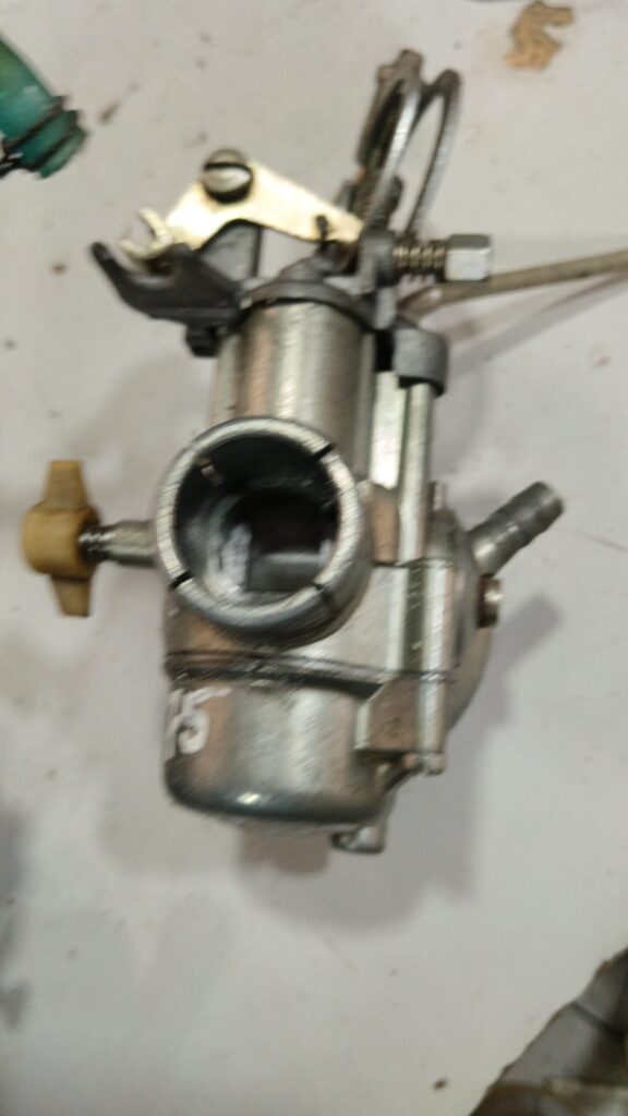 Toma de admisión trasera y cuba de carburador SHBC 19-19 para Vespa PK 75. Muestra la abrazadera de conexión al motor.