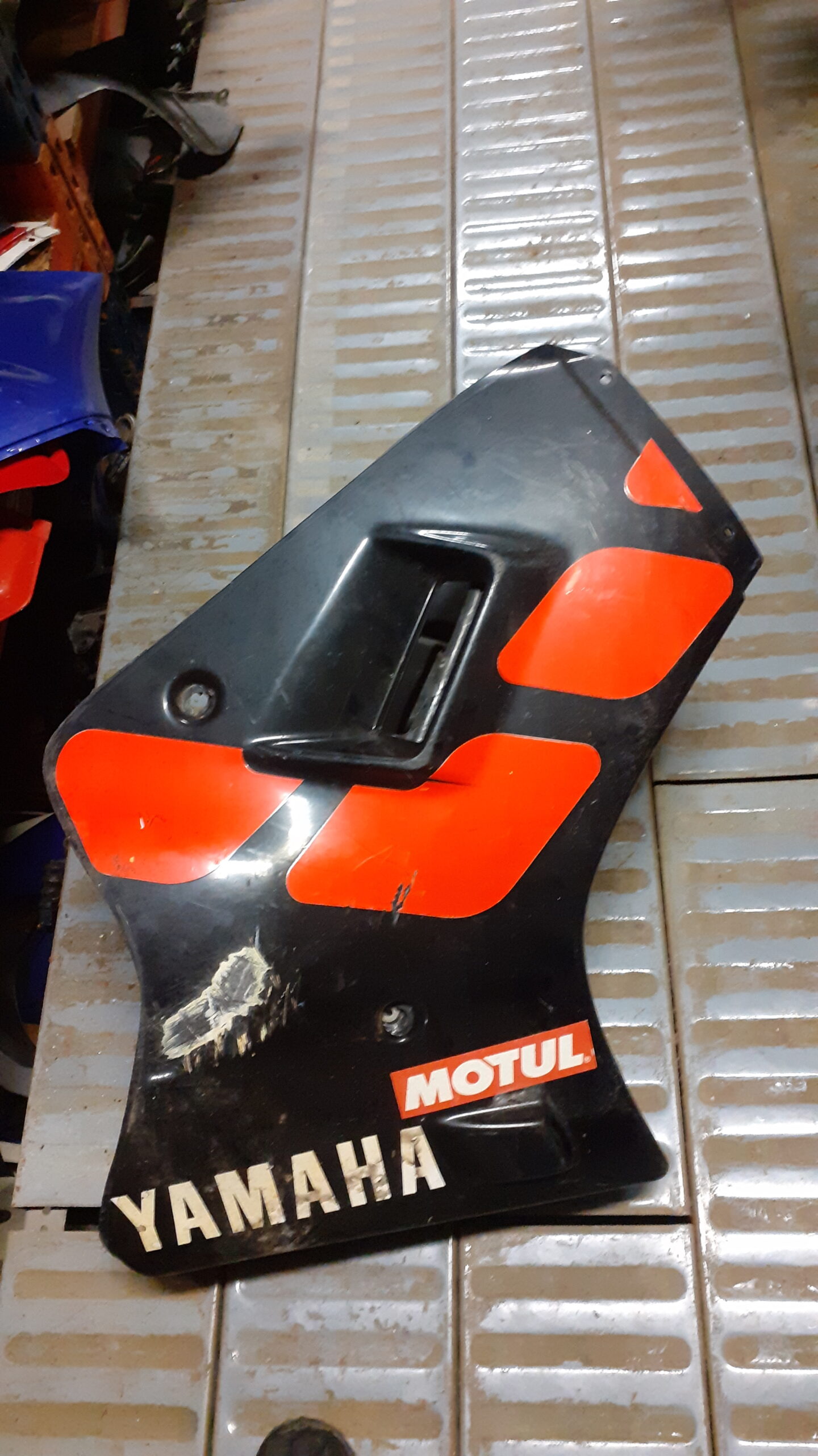 Carenado lateral derecho usado para Yamaha TZR 80 (1989-90). Color negro con adhesivos rojos, Motul y marca Yamaha visibles.