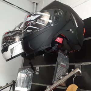 Cascos de moto abatibles NOX en negro mate y blanco brillante. Exposición en tienda con visores solares integrados.