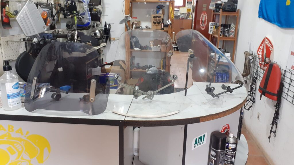 Cúpulas y parabrisas para moto usados, modelos ahumados y transparentes en mostrador de tienda de recambios. Asturias.