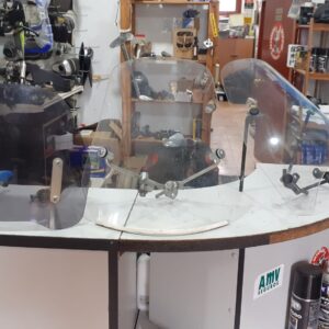 Cúpulas y parabrisas para moto usados, modelos ahumados y transparentes en mostrador de tienda de recambios. Asturias.