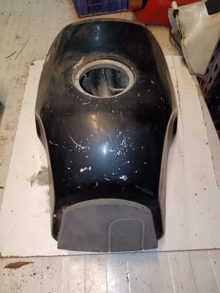 Vista posterior del depósito negro de BMW K75 usado, mostrando la zona de unión con el asiento y marcas de uso en la pintura.