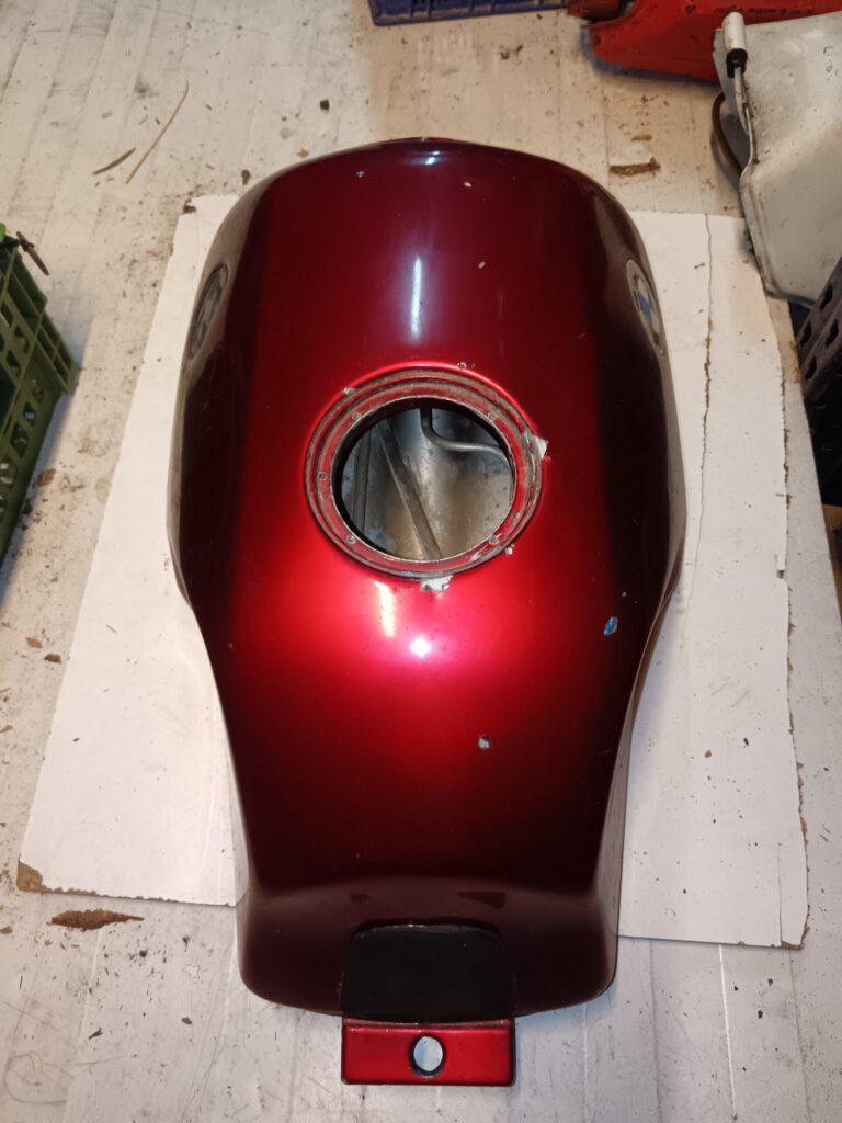 Depósito de combustible original BMW K75 usado, color rojo brillante, vista superior con boca de llenado abierta y marcas de uso.