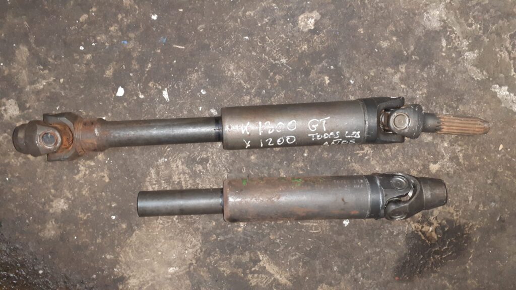 Dos ejes cardán de transmisión usados para motos BMW K1200 y K75. Vista paralela sobre suelo de taller.