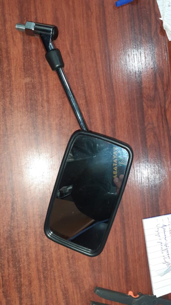 Espejo retrovisor derecho para Suzuki Burgman 250 de segunda mano. Cristal y brazo negro sobre mesa de madera.