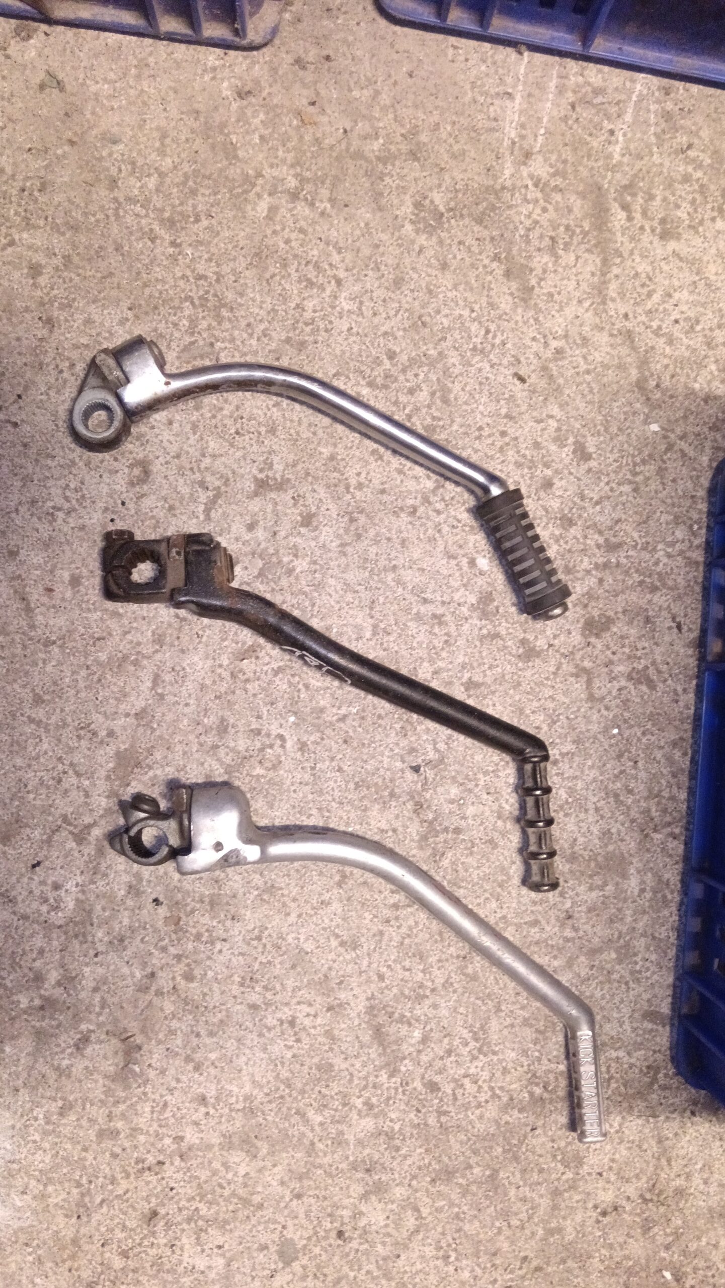 Plano detalle de tres palancas de arranque para motos clásicas. Se aprecian las texturas, el estriado y una referencia manuscrita.