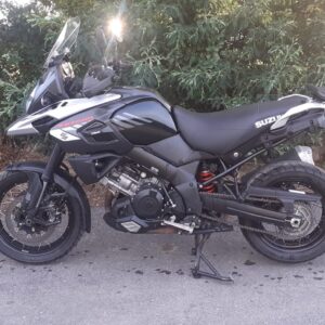 Vista de perfil completo de Suzuki V-Strom 1000 2018 negra con llantas de radios en carretera, sobre caballete central.