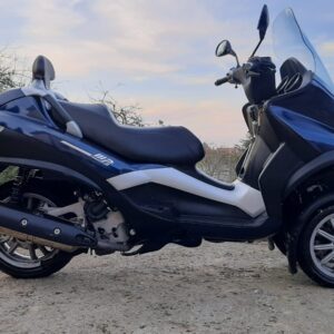 Vista lateral derecha de Piaggio MP3 400 azul (2008), mostrando escape y motor, en VAYAFABA Asturias.