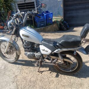 Moto Yamaha Special 250 blanca de segunda mano en estado original, vista lateral izquierda aparcada en un desguace.