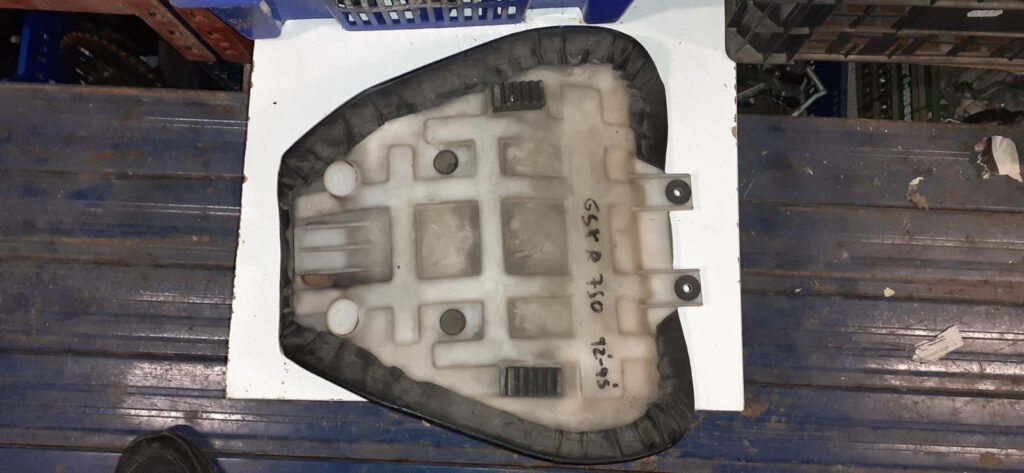 Vista inferior de la base de plástico de un asiento delantero usado de Suzuki GSX-R 750 (1992-1995) sobre una estantería.