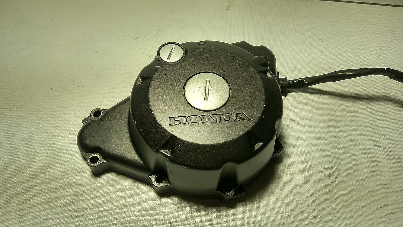 Perspectiva lateral exterior de la carcasa de estátor y alternador original negra con logotipo en relieve para Honda CBR 125 R años 2004 a 2006.