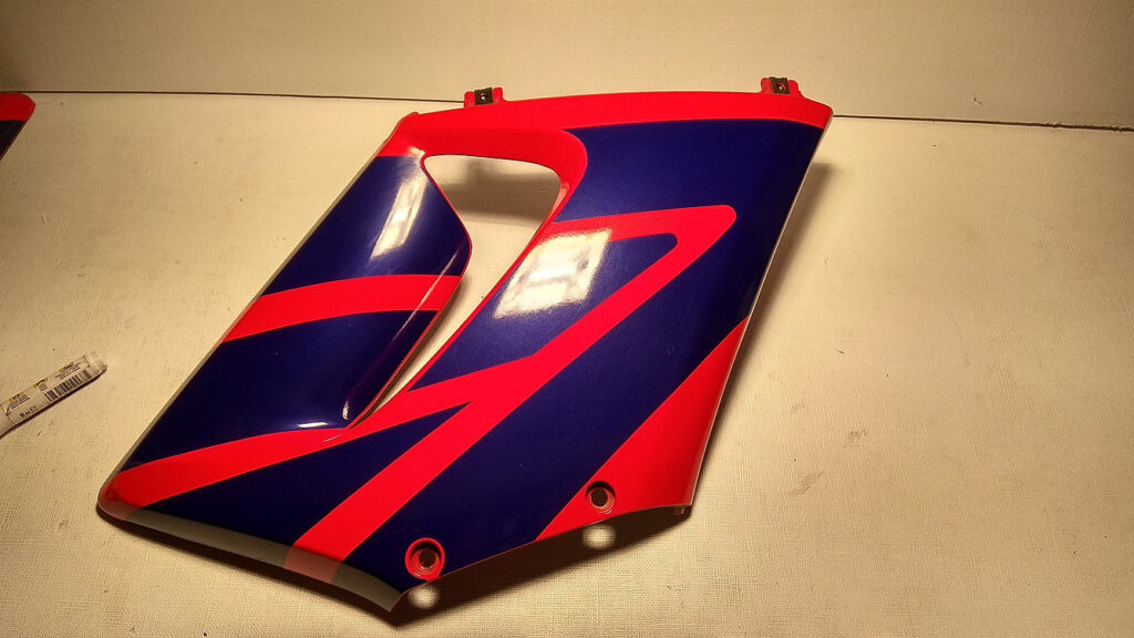 Carenado lateral derecho original azul y rojo con soportes superiores metálicos sanos para motocicleta Honda CBR 125 R.