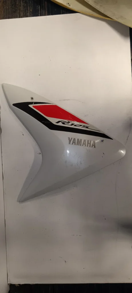 Carenado lateral derecho Yamaha YZF-R125 blanco con vinilos originales en rojo y negro. Recambio original 2014-2018.