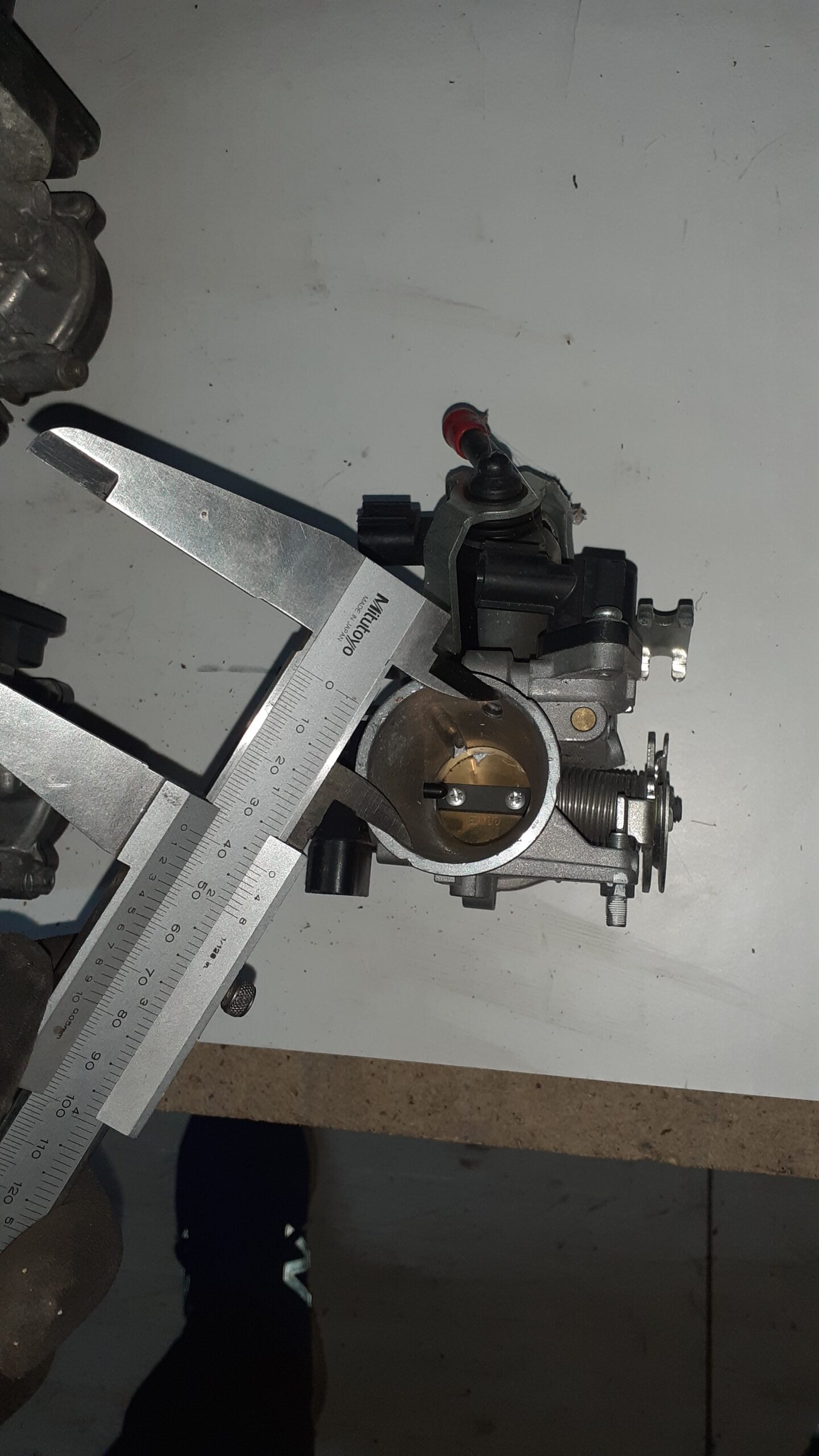 Cuerpo de inyección de Suzuki Burgman 125 con detalle de sensores electrónicos, conectores y toma de combustible superior.