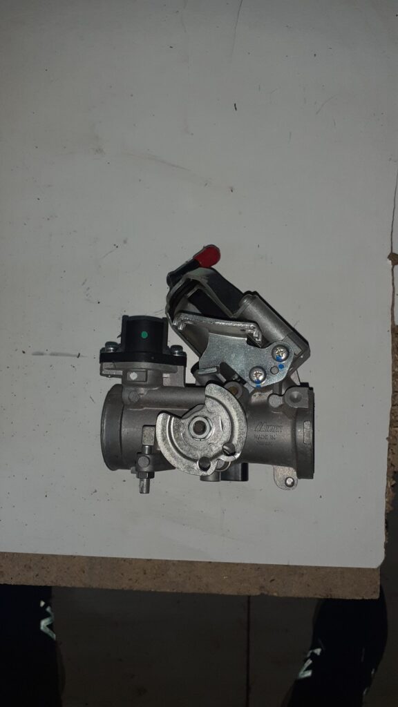 Vista de perfil del cuerpo de inyección para Suzuki Burgman 125 con detalle de la polea del acelerador y sensores de control.