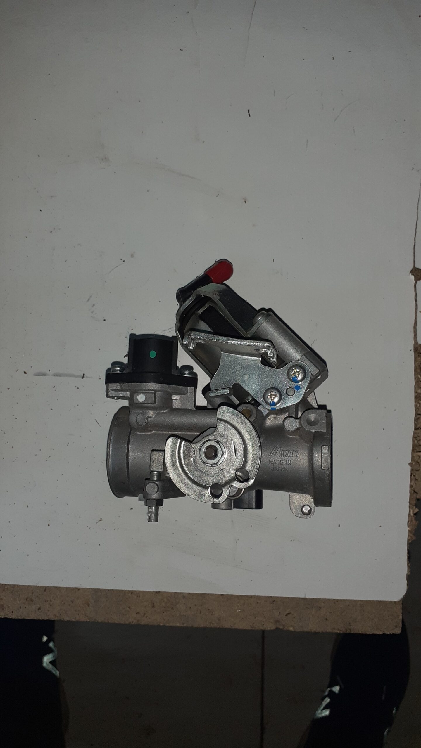 Vista de perfil del cuerpo de inyección para Suzuki Burgman 125 con detalle de la polea del acelerador y sensores de control.