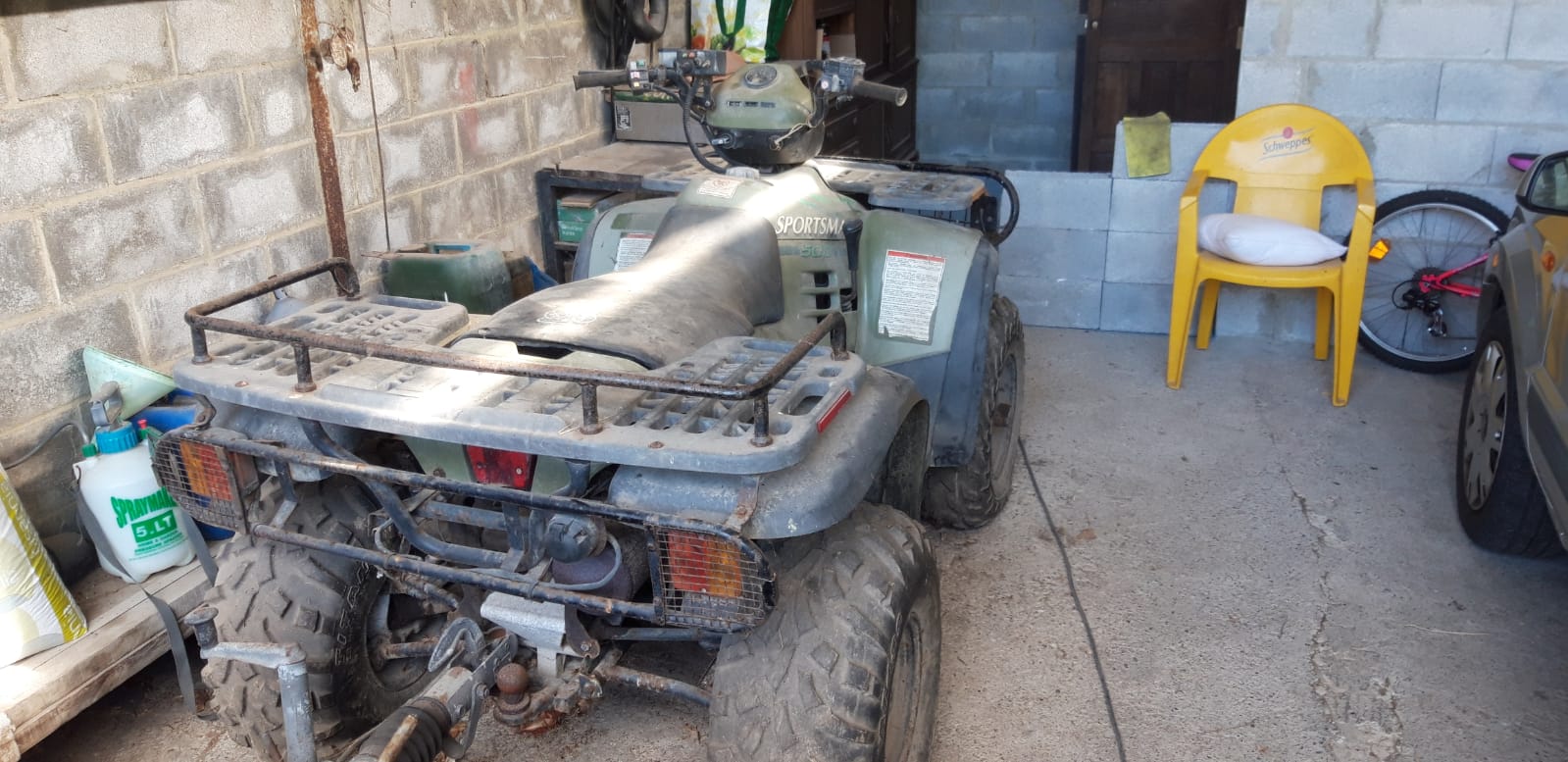 Vista trasera del despiece de Polaris Sportsman 500 (2000) mostrando pilotos, parrilla de carga y neumáticos traseros.