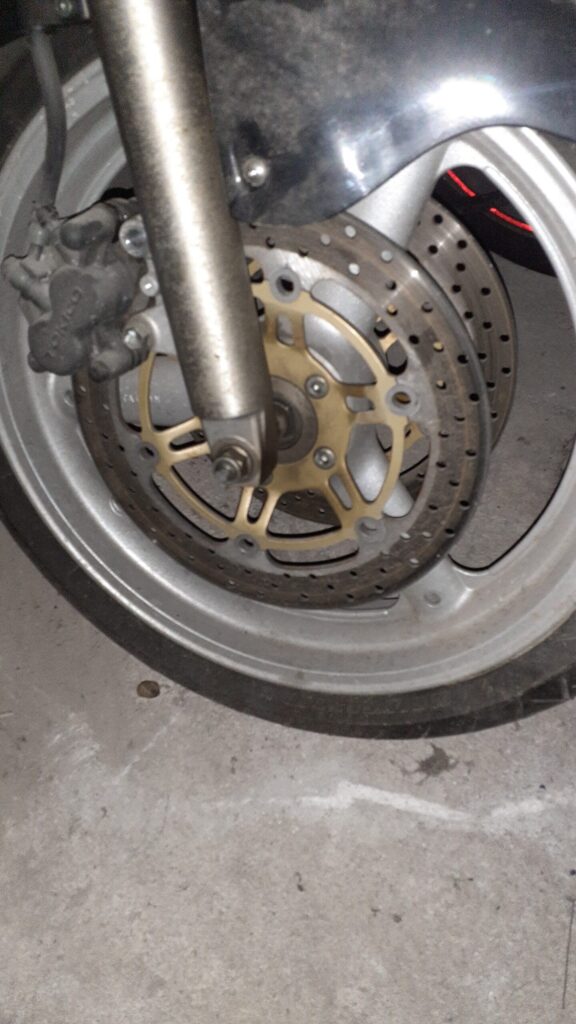 Discos de freno delanteros con núcleo dorado montados en la rueda de una Suzuki Bandit 600 año 2004, con pinza de freno.
