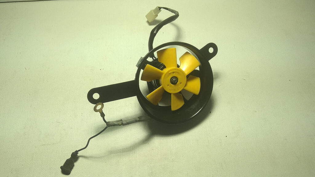 Vista frontal del electroventilador de radiador original con hélice amarilla de seis aspas para motocicleta Honda CBR 125 R años 2004 a 2006.