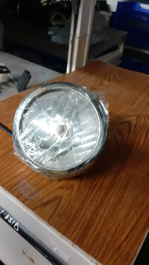 Faro delantero original recuperado para motocicleta Cagiva Electra 125 (1989), óptica con cerquillo cromado.