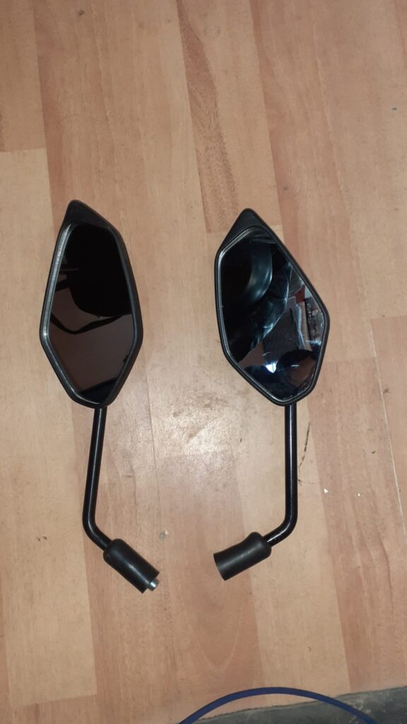 Un par de espejos retrovisores negros angulares para el scooter Yamaha XMAX 125, mostrados sobre una superficie de madera.