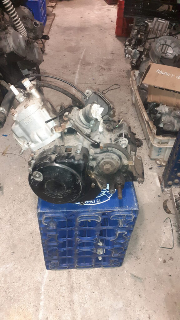 Motor completo Honda NSR 125 JC22 de dos tiempos. Vista general del bloque motor revisado sobre soporte azul en taller.