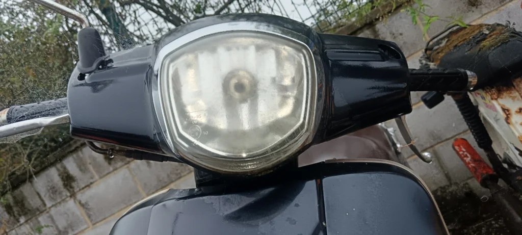 Óptica de faro delantero para Kymco Like. Recambio original, lente transparente y carcasa negra. Estado verificado.