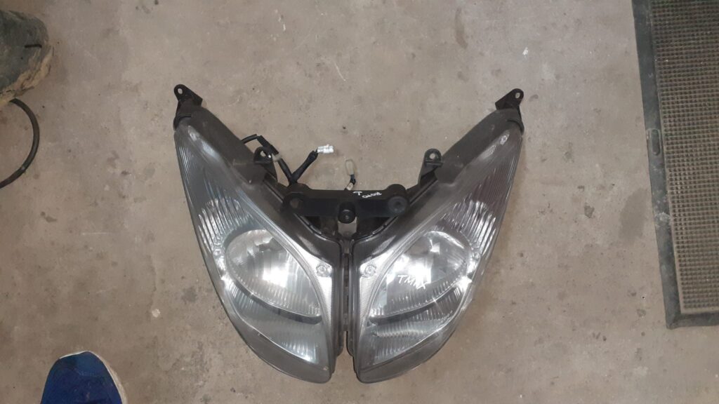 Óptica de faro delantero original para Yamaha T-Max 500. Recambio recuperado y revisado con patillas y conectores intactos.