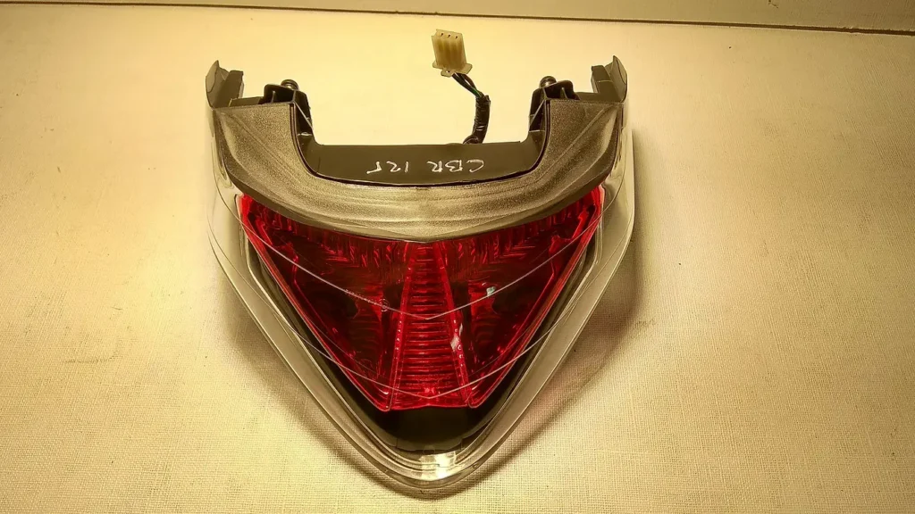Perspectiva superior del grupo óptico trasero original con tulipa de freno roja y mazo de cables para Honda CBR 125 R.