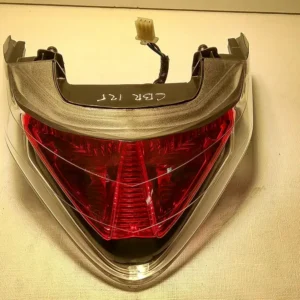 Perspectiva superior del grupo óptico trasero original con tulipa de freno roja y mazo de cables para Honda CBR 125 R.