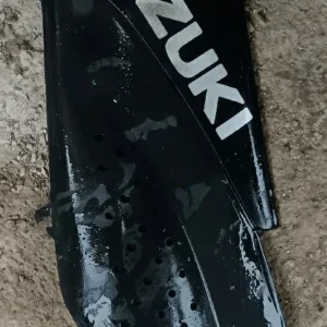 Quilla lateral izquierda para Suzuki Katana 50cc en color negro con logo Suzuki blanco. Recambio original de carrocería.
