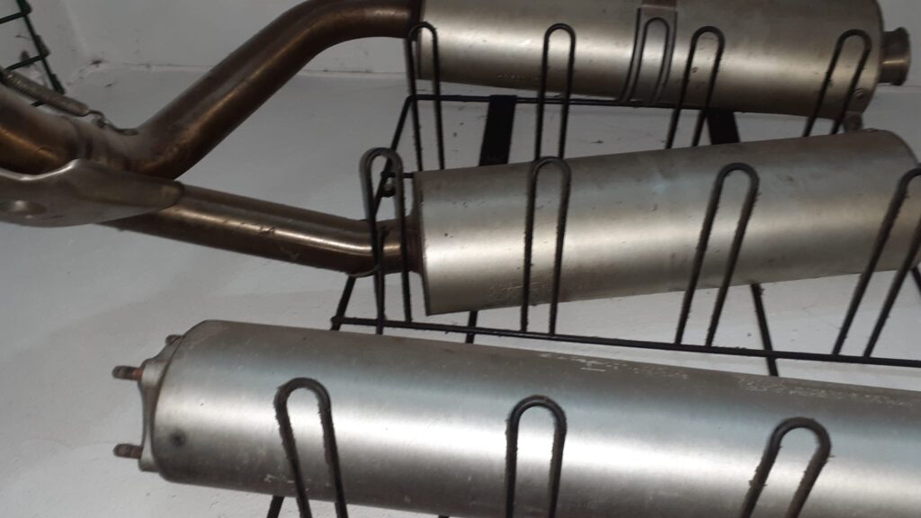 Silenciosos de escape Termignoni para Ducati 996 y 748, ubicados en una estantería de metal negra en un taller.