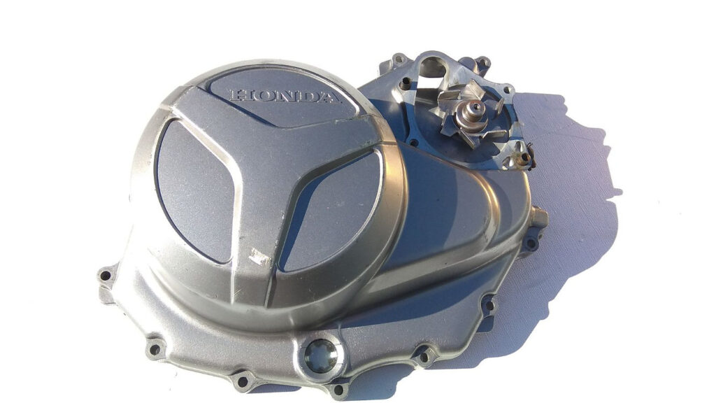 Vista exterior de la tapa de embrague original con mirilla de aceite y módulo de bomba de agua integrado para Honda XL 1000 V Varadero.