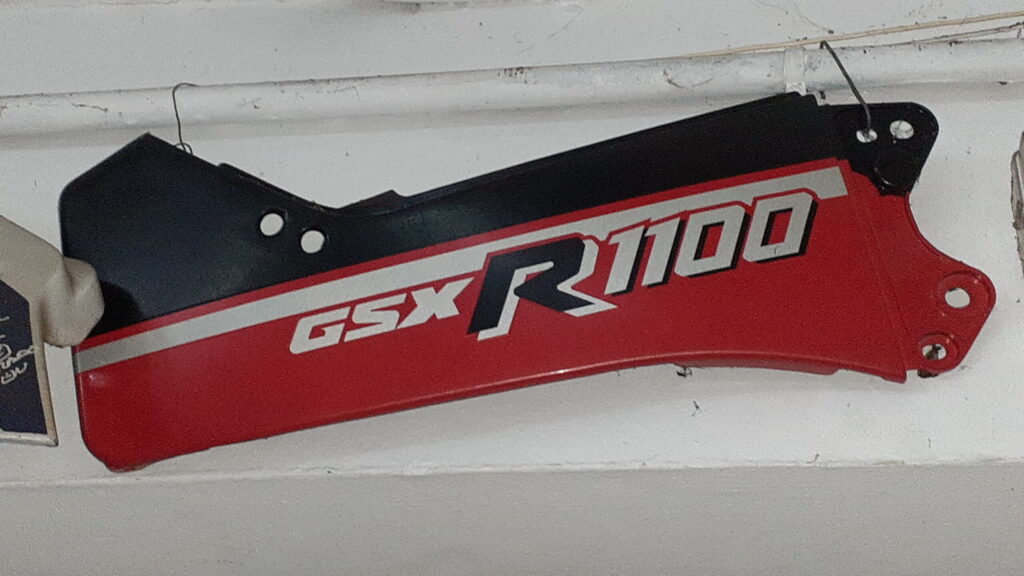 Tapa lateral trasera derecha original para Suzuki GSX-R 1100 (1987), carenado en color rojo y negro con gráficos oficiales.