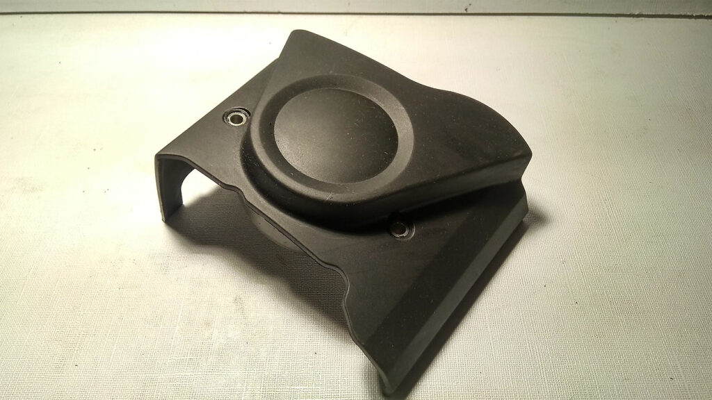 Vista exterior de la tapa de piñón de ataque original de plástico negro para la transmisión de la motocicleta Honda CBR 125 R.