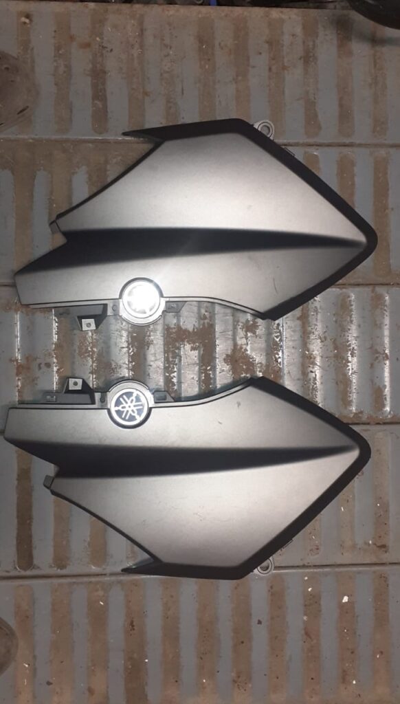 Juego de tapas laterales traseras para Yamaha X-MAX 125 (2017) en color gris mate, recambio original con emblemas Yamaha incluidos.
