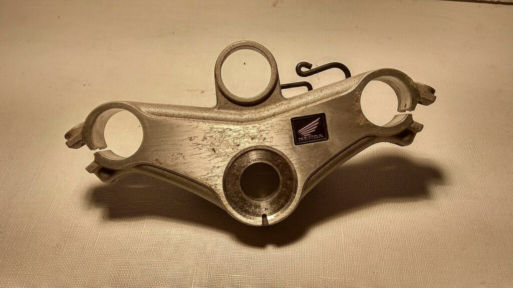 Vista superior de la tija de dirección original en aluminio pulido con emblema de resina para horquilla de Honda CBR 125 R años 2004 a 2006.