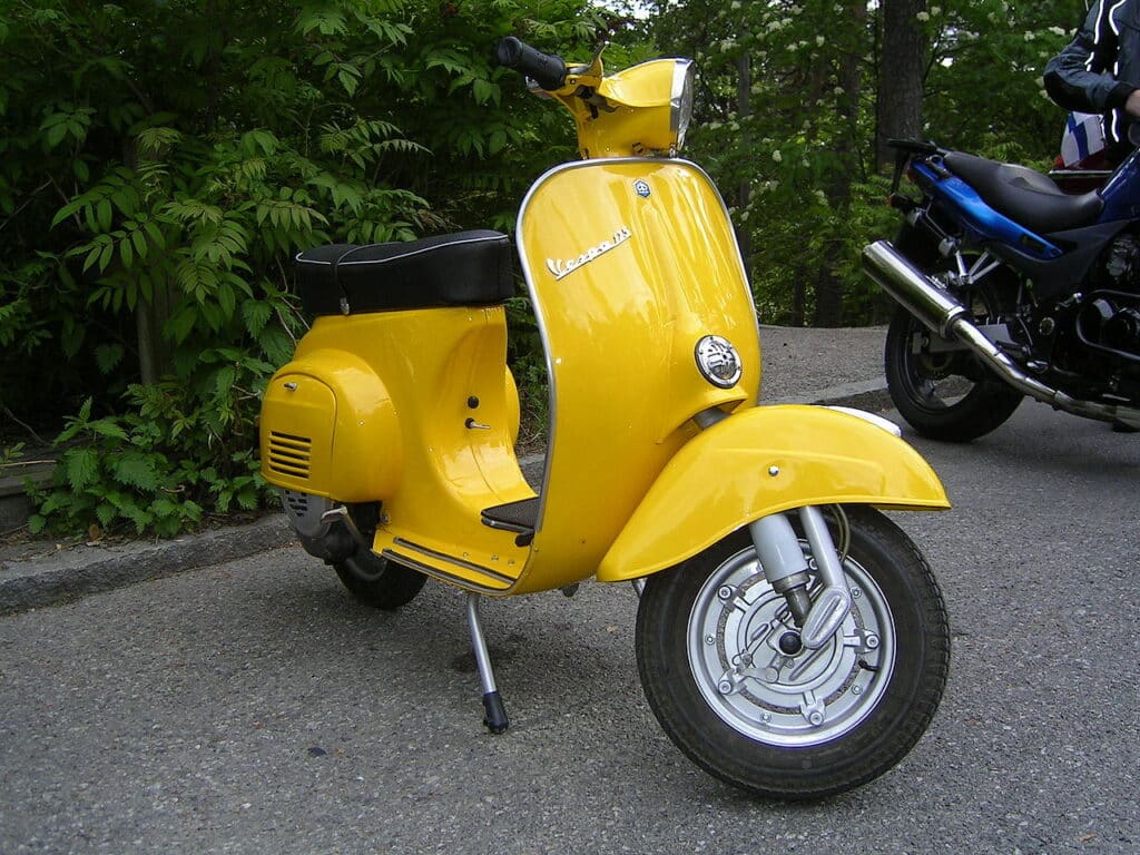 Vespa Primavera 125 amarilla aparcada, un ejemplo de diseño italiano auténtico y artesanía frente a las copias industriales.